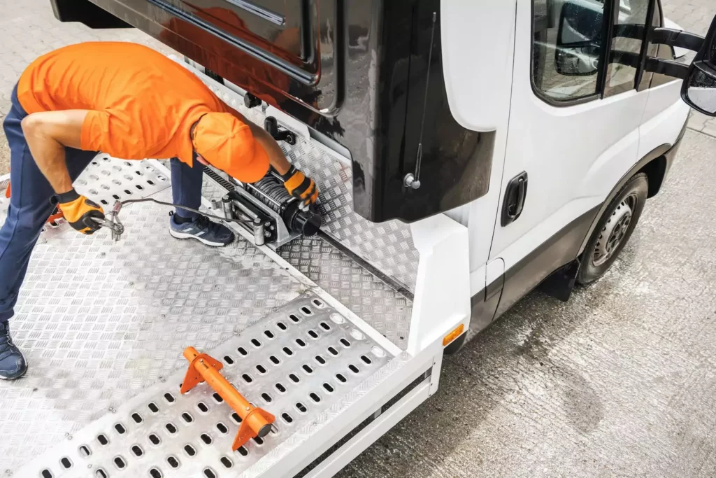 Sleepwagenchauffeur klaar om de auto te laden met behulp van een lier